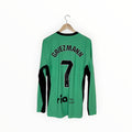 A green long-sleeve soccer jersey with 'GRIEZMANN' and the number '7' printed in black on the back, hanging on a wooden hanger against a plain white background.