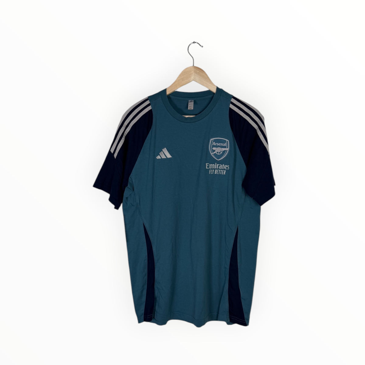 A dark teal Adidas Arsenal short-sleeve athletic t-shirt hanging on a wooden hanger against a plain white background. The shirt features navy blue side panels, dark navy sleeves with white stripes, and white printed logos for Adidas and Emirates Air Lines.