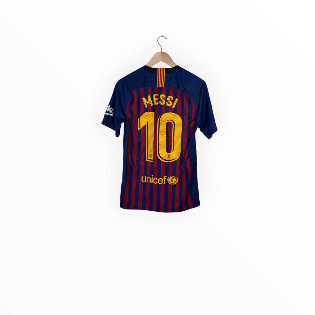 Back view of a Barcelona soccer jersey with 'MESSI 10' and 'unicef' printed on it, hanging on a wooden hanger against a white background.