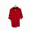 A red Belgium national football team jersey by Nike, featuring a black and gold collar, black and gold sleeve stripes, and the Belgian crest on the chest, hanging on a wooden hanger against a white background.