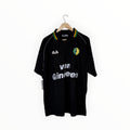 A vintage black Alva football jersey with 'van Gineen' sponsor text, hanging on a wooden hanger against a white background.