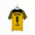 A yellow and black Borussia Dortmund soccer jersey with 'DORTMUND', the number '9', and 'HAALAND' printed on the back, hanging on a wooden hanger against a white background.