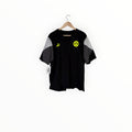 A black Borussia Dortmund short-sleeve t-shirt with gray color-blocked sleeves, hanging on a wooden hanger against a plain white background.