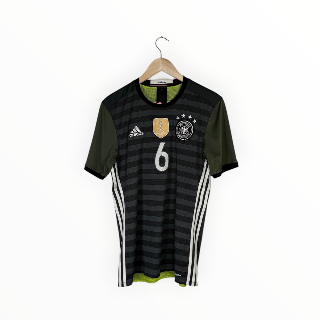 A Germany national football team home jersey with dark gray and black horizontal stripes, olive green sleeves, white Adidas branding and number 6, hanging on a wooden hanger against a white background.