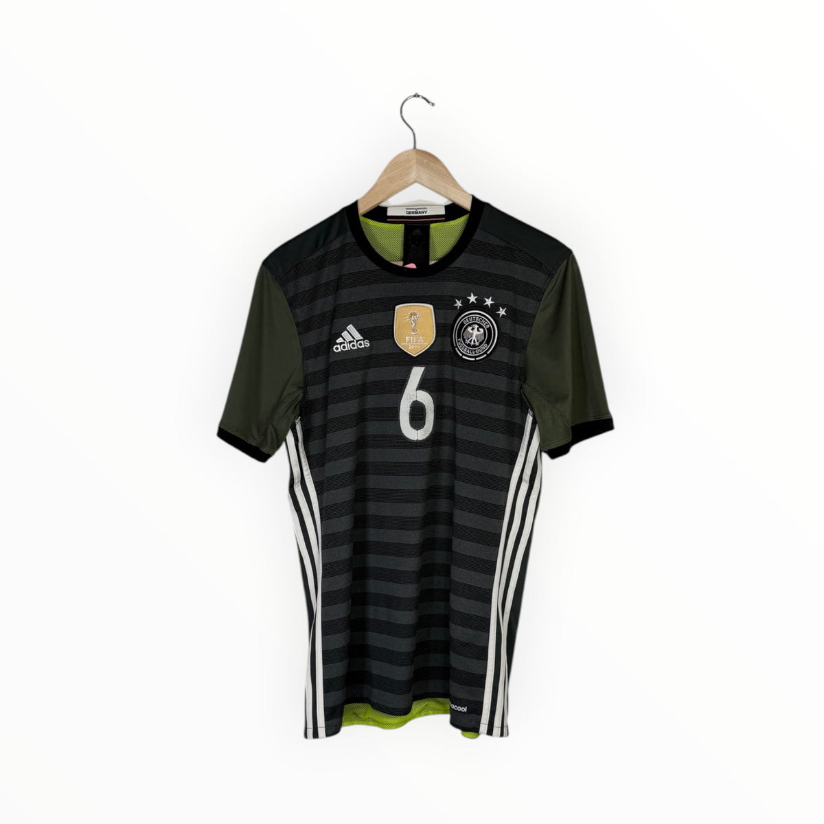 A Germany national football team home jersey with dark gray and black horizontal stripes, olive green sleeves, white Adidas branding and number 6, hanging on a wooden hanger against a white background.