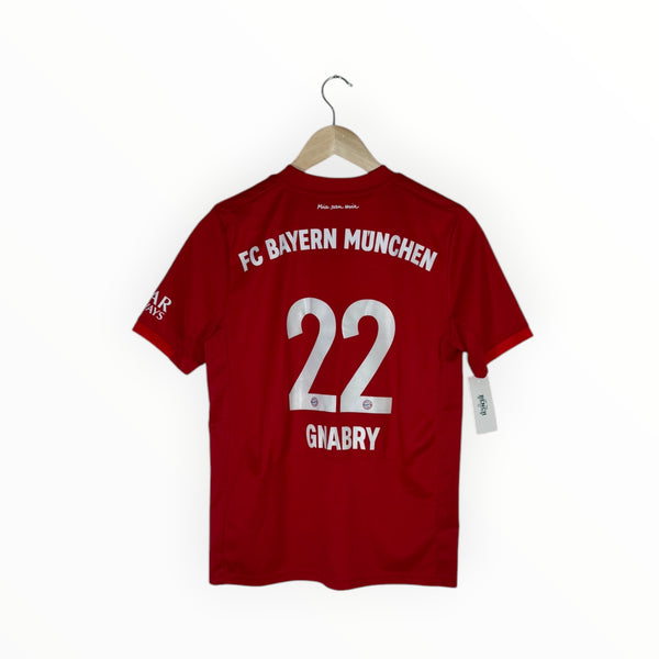 A red FC Bayern Munchen short-sleeve soccer jersey with '22 GNABRY' printed in white on the back, hanging on a wooden hanger against a plain white background.