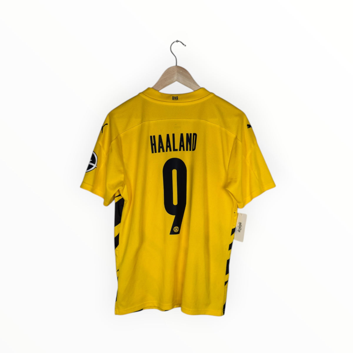 A yellow Borussia Dortmund soccer jersey with 'HAALAND' and the number '9' printed in black on the back, hanging on a wooden hanger against a white background.