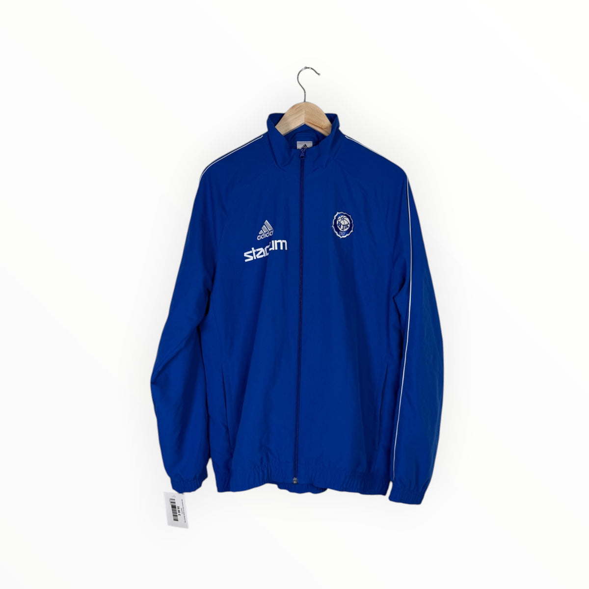 A royal blue Adidas track jacket with white logos and stripes, hanging on a wooden hanger against a plain white background.