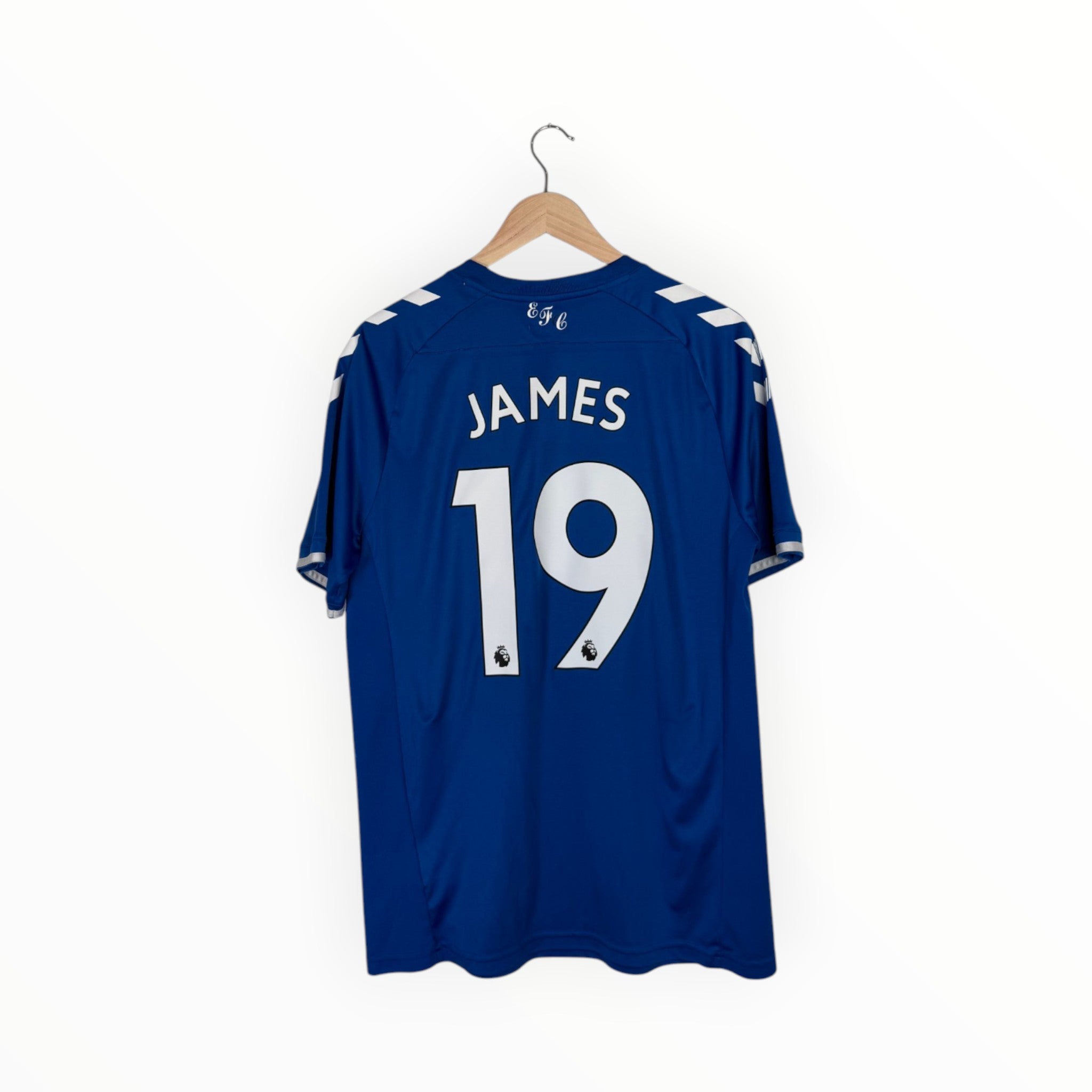 A royal blue short-sleeve soccer jersey hanging on a wooden hanger against a plain white background. The back of the jersey features the name 'JAMES' and the number '19' in white.