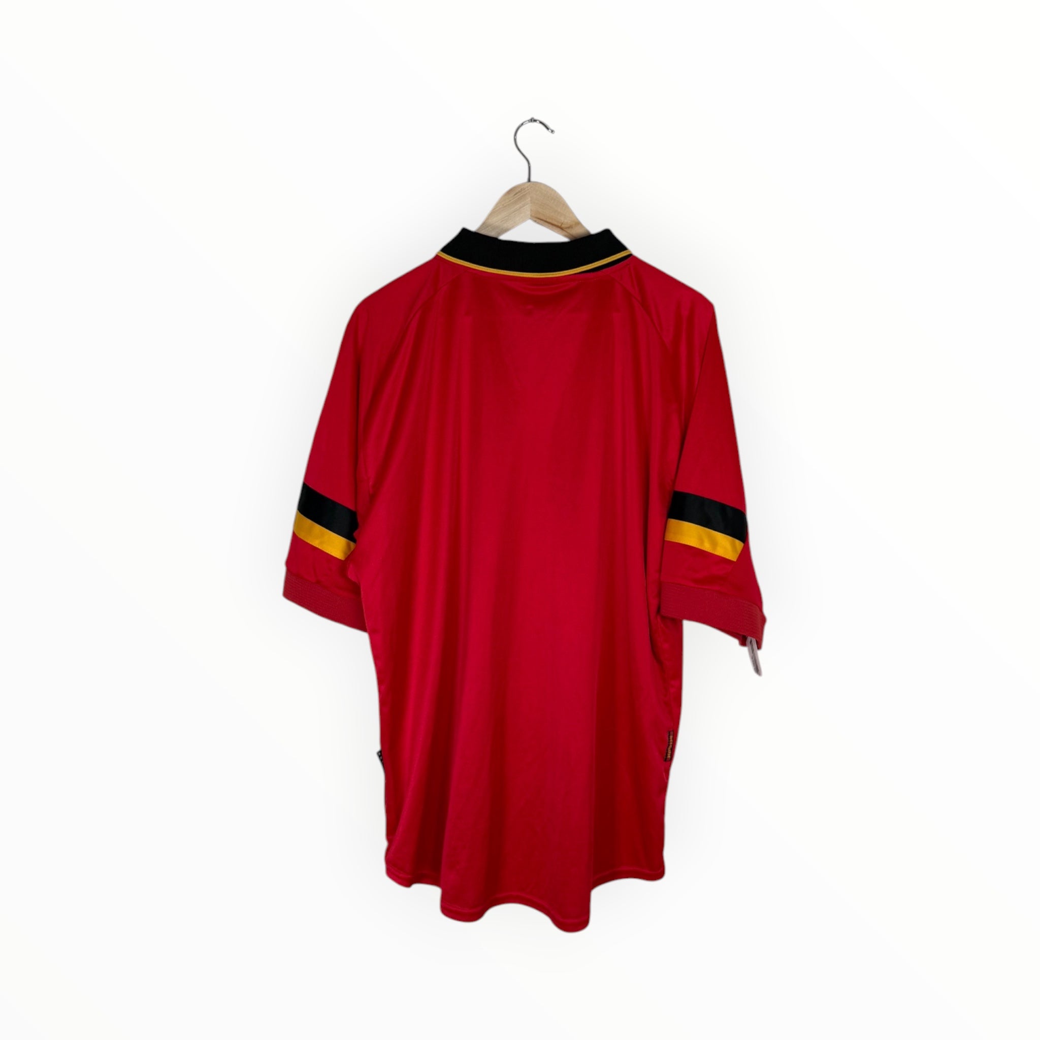 A red short-sleeve athletic jersey hanging on a wooden hanger against a plain white background. The jersey features a black collar with thin gold trim and black and gold stripes on the sleeves.