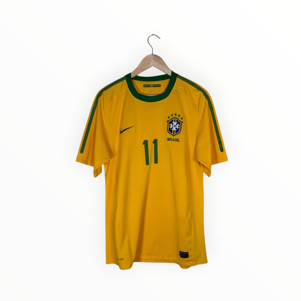 A yellow Brazil national football team jersey with green trim, featuring the number 11 on the front, hanging on a wooden hanger against a white background.