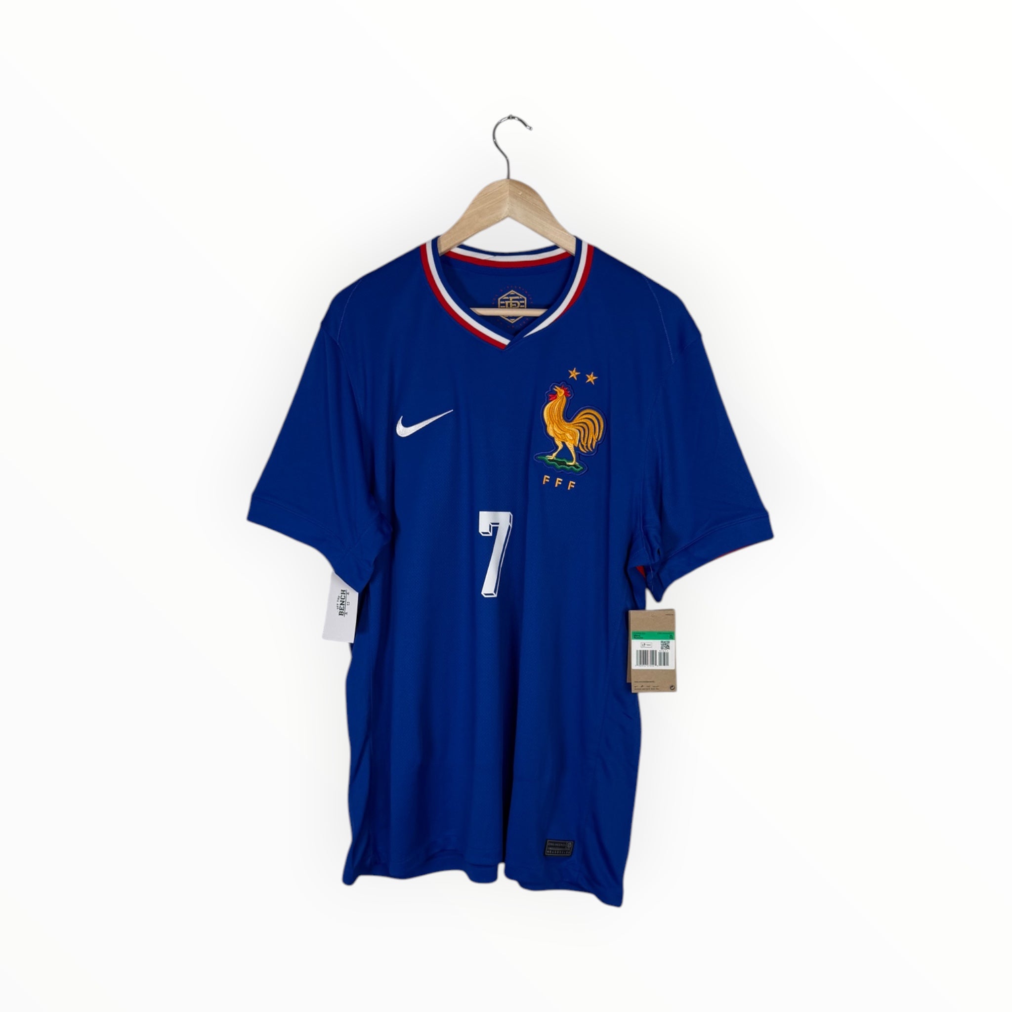 A blue France national football team jersey by Nike, featuring the number 7, the rooster crest, and a white Nike swoosh, hanging on a wooden hanger against a white background.