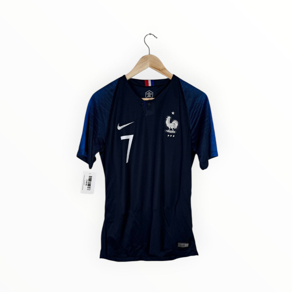 A dark navy blue France soccer jersey with the number 7, featuring a white Nike swoosh and the French national team rooster crest, hanging on a wooden hanger against a white background.