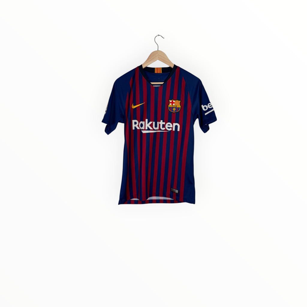 FC Barcelona home soccer jersey with navy and red vertical stripes, featuring the Nike swoosh, FC Barcelona crest, and Rakuten sponsor logo, hanging on a wooden hanger against a white background.