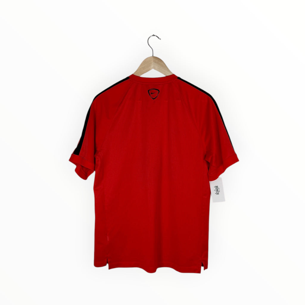 A red short-sleeve athletic jersey with black stripes down the sleeves, hanging on a wooden hanger against a plain white background.