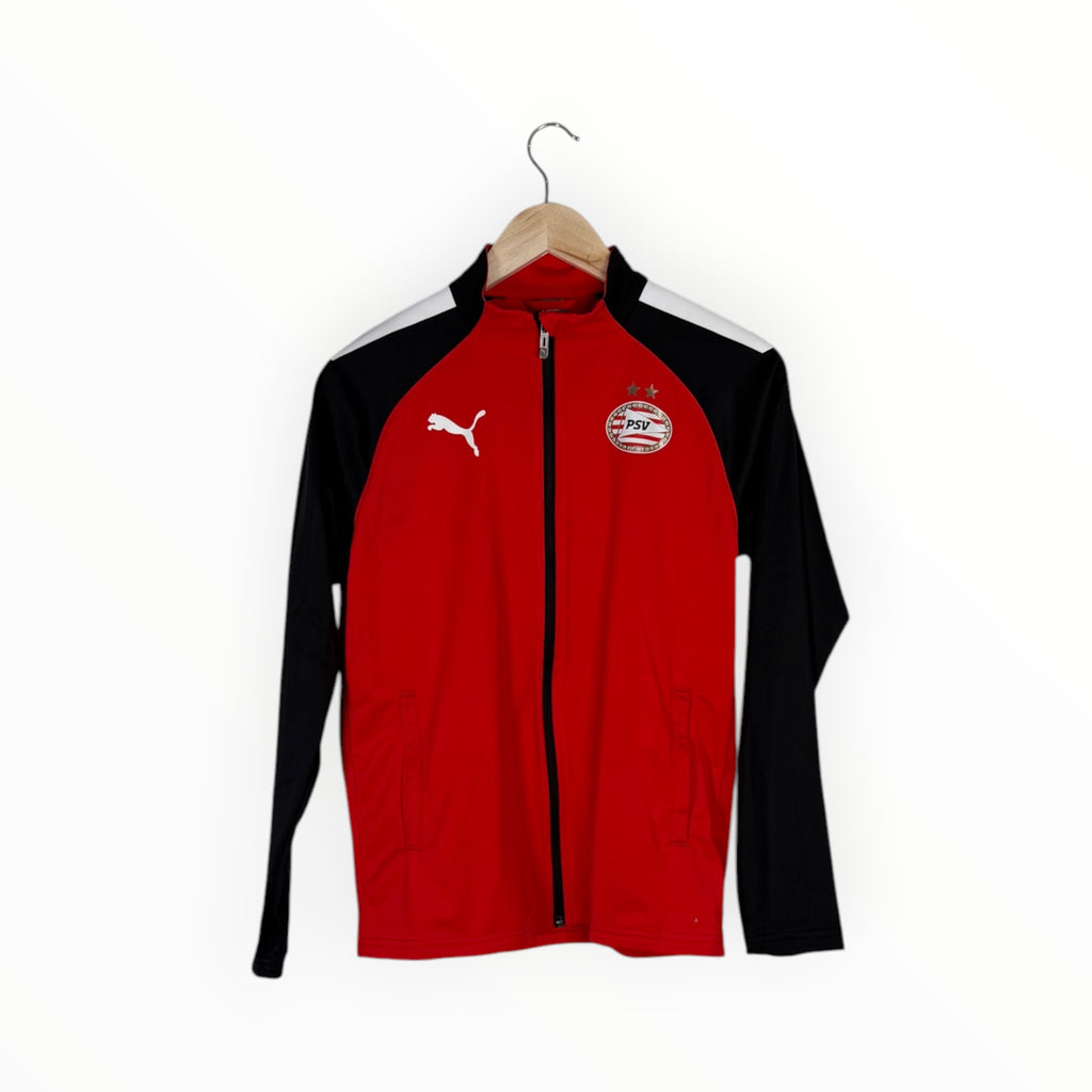 A red and black Puma track jacket with white shoulder stripes, hanging on a wooden hanger against a plain white background.