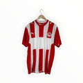 A red and white vertically striped Puma football jersey hanging on a wooden hanger against a plain white background.