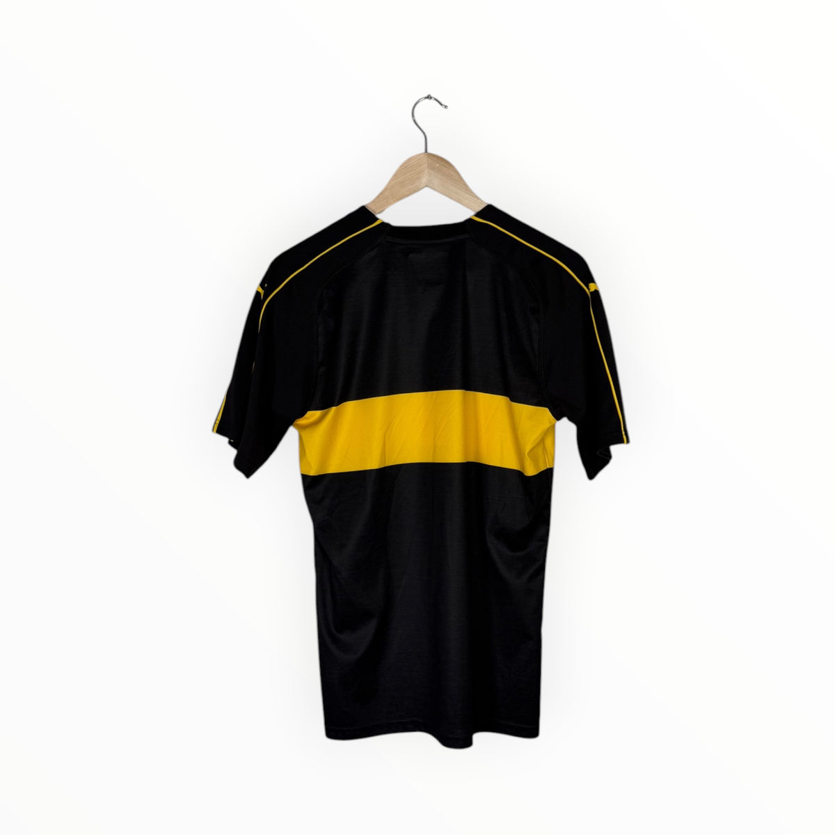 A black short-sleeve athletic jersey with a bold yellow horizontal stripe across the chest and yellow piping along the shoulders, hanging on a wooden hanger against a plain white background.