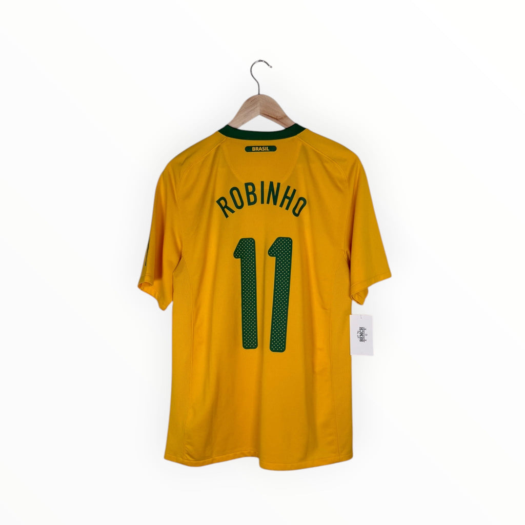 A yellow Brazil soccer jersey with 'ROBINHO' and the number '11' printed in green on the back, hanging on a wooden hanger against a white background.