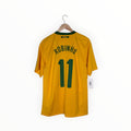 A yellow Brazil soccer jersey with 'ROBINHO' and the number '11' printed in green on the back, hanging on a wooden hanger against a white background.