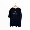 A black FILA t-shirt hanging on a wooden hanger against a plain white background. The shirt features the FILA logo in white outlined lettering across the chest and a small red and gold club crest above it.